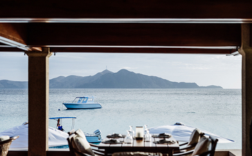 安缦璞乐度假村餐厅内景，可俯瞰平静海湾和远处山峦。