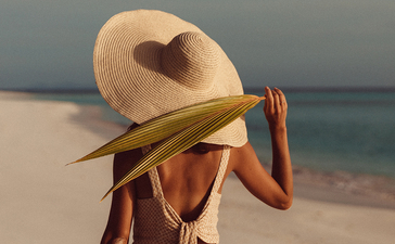 安缦璞乐度假村海滩上，客人戴着宽檐帽眺望大海。