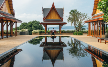 Amanpuri villa pool reflecting traditional Thai architecture and manicured gardens.