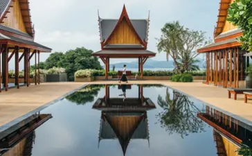 Villa pool with Thai temple reflected in still water at Amanpuri resort, Thailand.