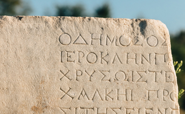 Ancient stone inscription at Amanruya with weathered Greek text carved into pale limestone.