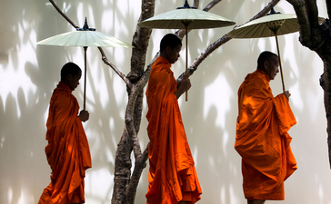 Buddhist monks in saffron robes walking amongst trees at Amansara.