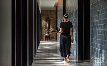 Woman walking through a modern corridor at Amansara wellness retreat.