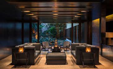 Amansara wellness space with sunken seating area, warm lighting, and garden views at dusk.