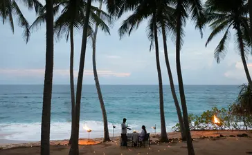Dining pavilion framed by palm trees overlooking the Indian Ocean at Amanwella.