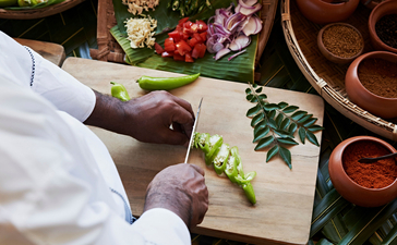 Freshly harvested vegetables on a wooden board at Amanwella, with terracotta pots nearby.