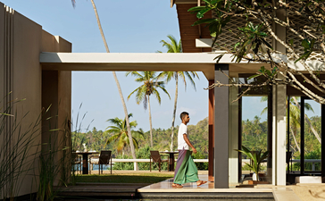 Amanwella villa with wooden pergola overlooking reflecting pool and palm trees.