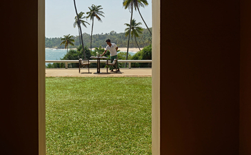 View from a pavilion across manicured lawns and palm trees towards the Indian Ocean at Amanwella.