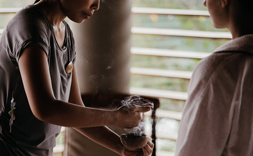 Two staff members exchanging a woven basket at Amanyara resort.