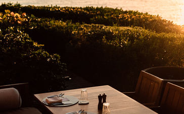 Dining table at sunset overlooking forested landscape at Amanyara resort.