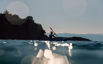 アマンゾイ・リゾートの青い海で、ゲストがカヤックを漕いでいる。