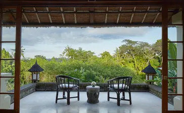 安缦黛宁度假村阿斯玛拉套房的露台，配有两把椅子，俯瞰绿色山景。