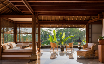 Ayung Suite at Amandari with wooden platform bed, floor cushions, and view onto tropical garden terrace.