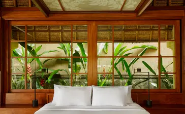 Valley Suite bedroom at Amandari with garden views through wooden-framed windows.