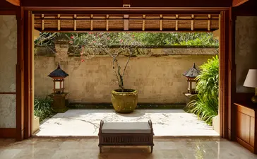 Valley Suite at Amandari with bed facing open courtyard and stone wall with climbing vines.