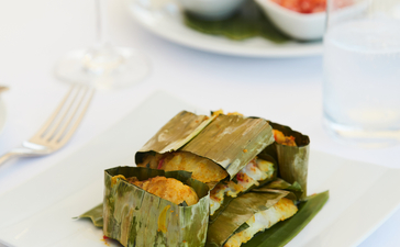 Grilled courgette slices arranged on a white plate at Amandira, with a fresh salad and white wine in the background.