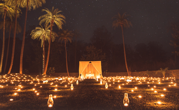 Candlelit dining pavilion beneath palm trees at Amanbagh at dusk.