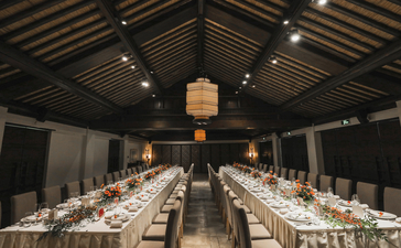 Wedding dining hall at Amanfayun with long tables set for guests beneath a timber ceiling.