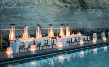 Candlelit wedding setup reflected in still water at Amangiri, with red rock cliff backdrop.