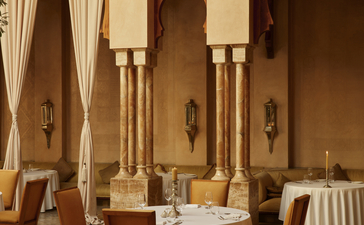 安缦珍纳餐厅内部，摩洛哥风格拱门和米色石柱环绕用餐区。