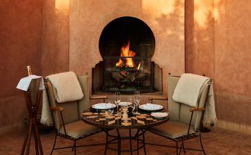 Al Hamra Maison dining area with fireplace at Amanjena, Morocco.
