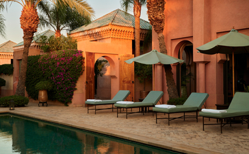 Al Hamra Maison courtyard with terracotta walls and loungers overlooking the pool at Amanjena.