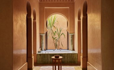 Maison accommodation at Amanjena with arched alcove featuring fresh flowers and traditional Moroccan architectural details.