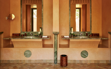 Amanjena accommodation pavilion with twin vanities and mirrors in warm-toned bathroom.