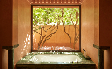 Pavilion soaking tub at Amanjena with view of gardens through window.