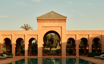 安缦珍纳度假村的摩洛哥式建筑，棕榈树点缀的庭院中央水池倒映着拱形走廊。