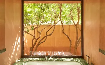 Salle de bains avec baignoire encastrée surplombant un jardin verdoyant à Amanjena.