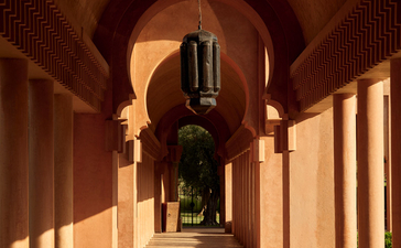 安缦珍纳度假村的拱形走廊，柱子投射长影，温暖的灯光照亮石墙。