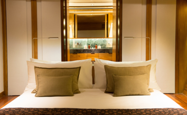 Principal bedroom at Amandira with illuminated mirror and golden cushions.