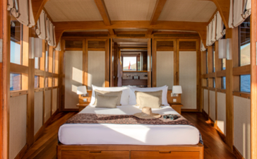 Principal cabin bedroom at Amandira with wooden interior and bed facing towards outdoor views.