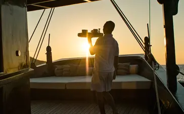 Silhouetted figure on the sundeck at Amandira during golden hour, overlooking the water.