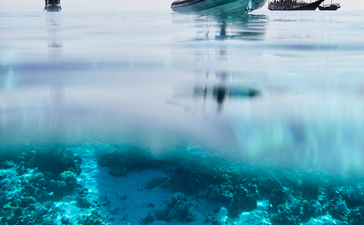 Diving boat Amandira anchored above a turquoise coral reef with clear waters.
