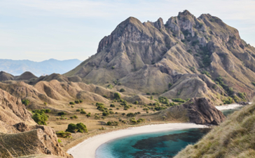 Dramatic volcanic peak rising above a crescent beach at Amandira, Indonesia.