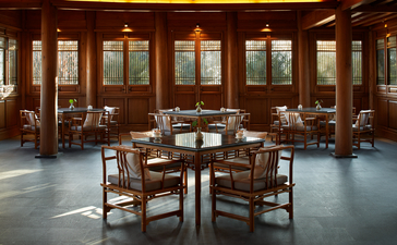 Dining room at Amandayan with round table, wooden chairs, and floor-to-ceiling windows overlooking natural surroundings.