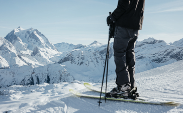 Skier on snowy mountain slope with Alpine peaks in background at Aman Le Mélézin.