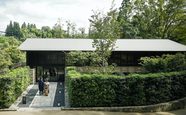 安缦京都度假村的现代建筑，屋顶被绿色植物覆盖，融入周围景观。