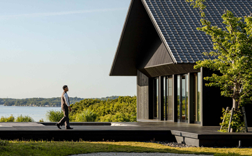 Modern black pavilion with pitched roof overlooking water at Amanemu resort, Japan.
