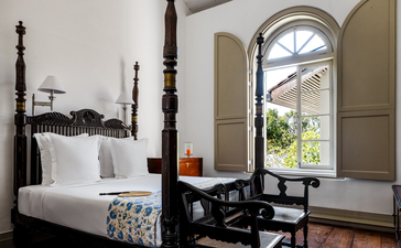 Principal bedroom with four-poster bed and arched window at Amangalla.