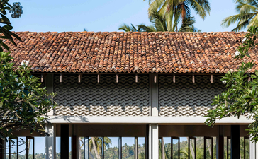 Pavilion with terracotta roof at Amanwella, framed by palm trees and tropical foliage.