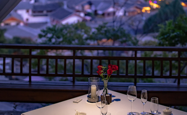 Dining table set for two at Amandayan with valley views illuminated at dusk.