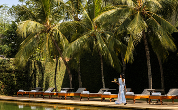 Palm trees line a tranquil waterway at Amangalla, their reflections mirrored in still green water.