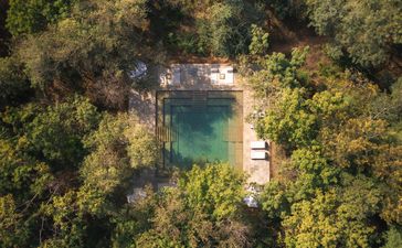 Aerial view of a rectangular swimming pool surrounded by dense woodland at Aman-i-Khas.