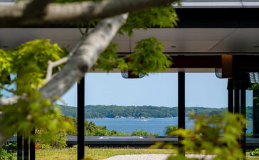 Amanemu resort exterior with modern pavilion framed by tree branches, overlooking coastal waters in Japan.