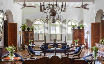 Amangalla's light-filled lounge with high ceilings, ornate chandelier, and period furnishings arranged around a central seating area.