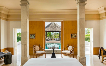 安缦齐和度假村花园套房，宽敞卧室配圆形柱廊、金色墙面和景观窗户。