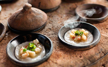 Culinary detail at Amanoi showing two plates of refined Asian cuisine on a textured surface with traditional serving vessels.